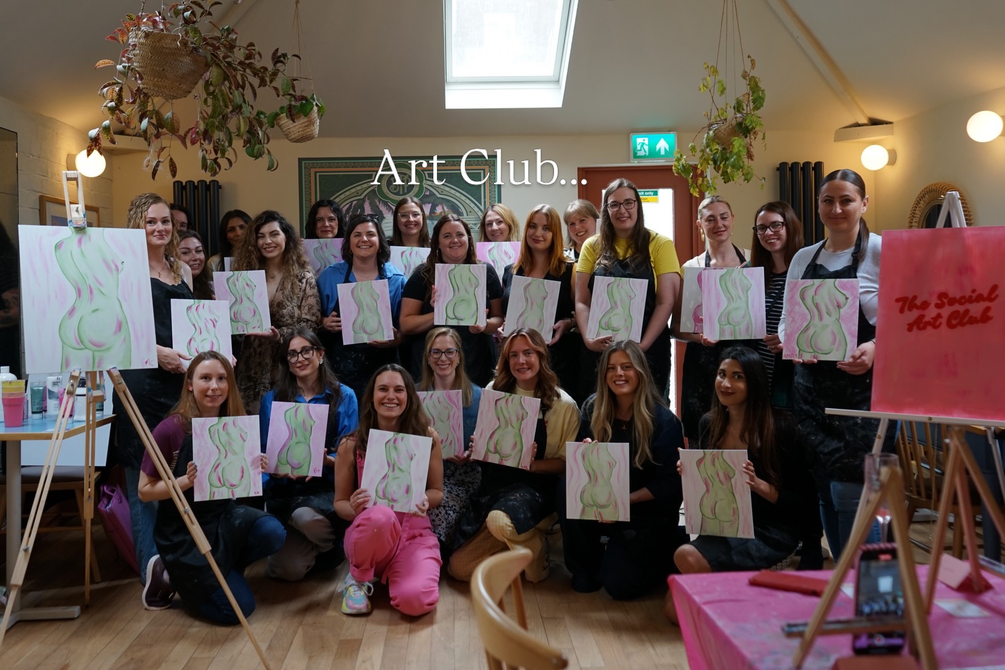 Members at an art club session holding their paintings